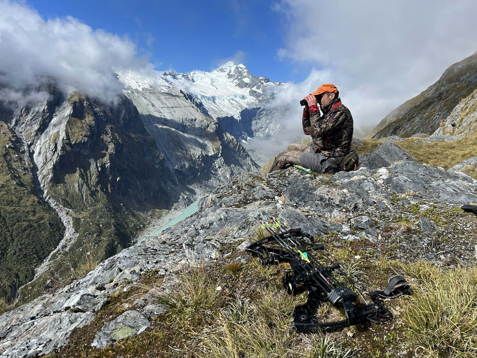 Daniel glassing with binoculars in the Southern Alps, bow in foreground